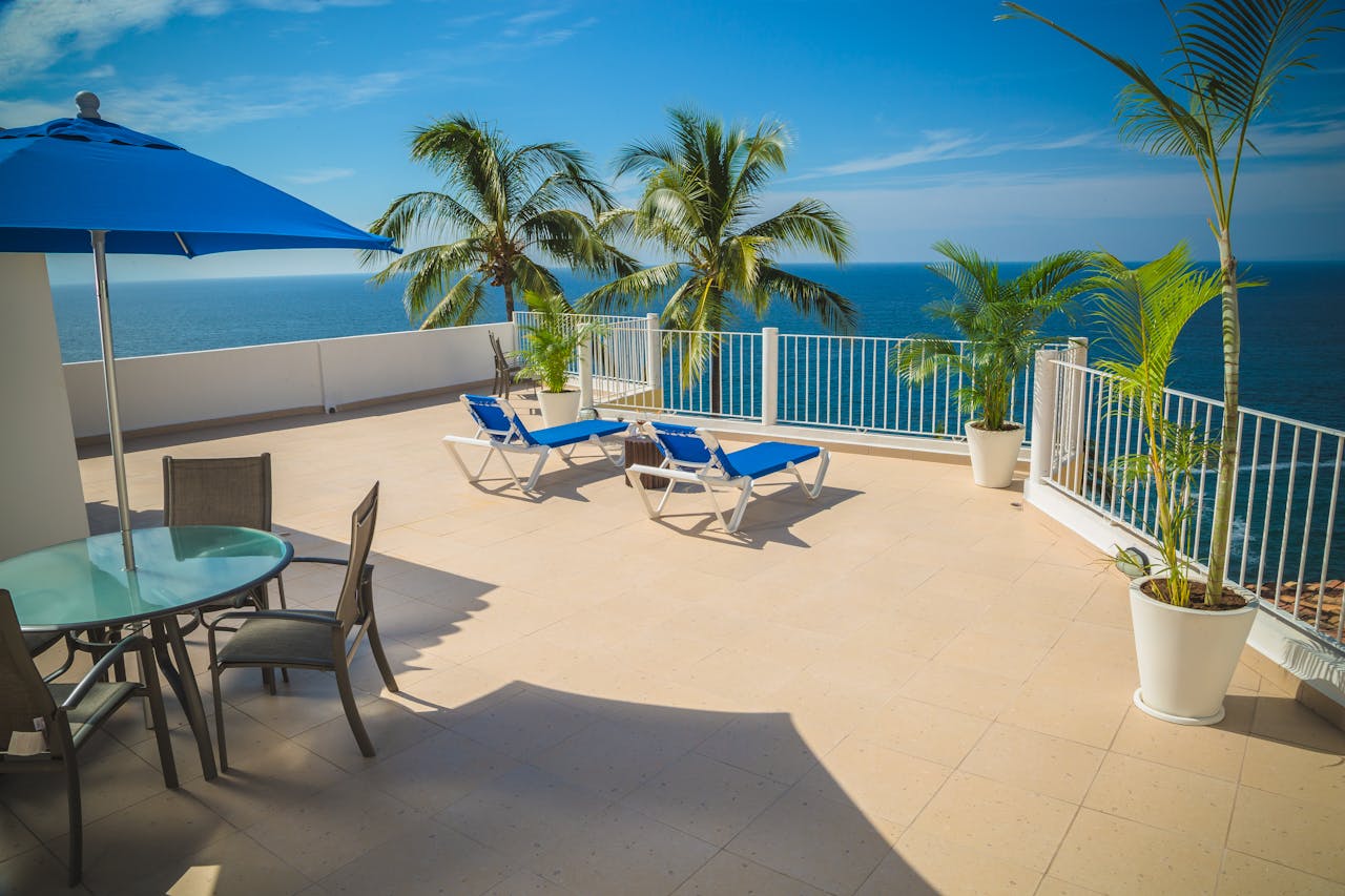 Relaxing beachfront terrace with lounge chairs and ocean view under blue skies.