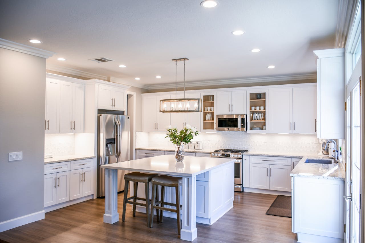 Elegant white kitchen featuring an island, modern appliances, and ample natural light.